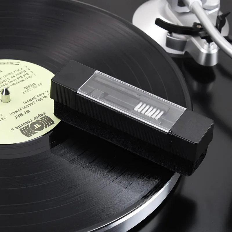 Black velvet record cleaning brush resting on a vinyl record on a turntable platter
